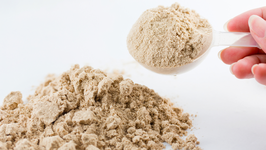 Measuring a scoop of magnesium glycinate powder from a pile