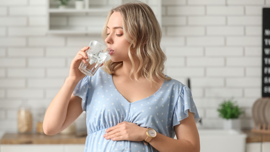 Pregnant woman drinking water after taking her magnesium glycinate supplement